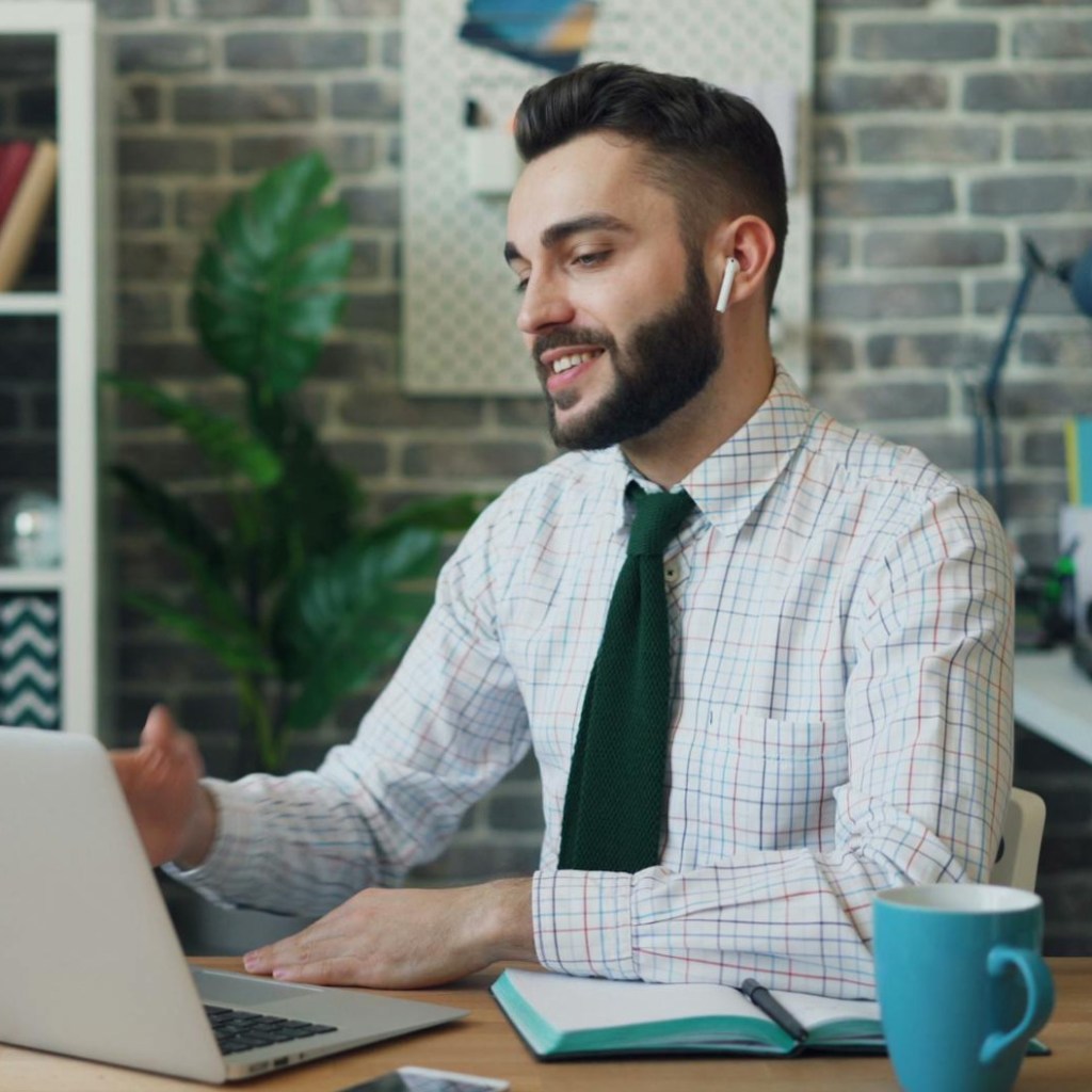 an office worker looking at the screen of his laptop and smiling